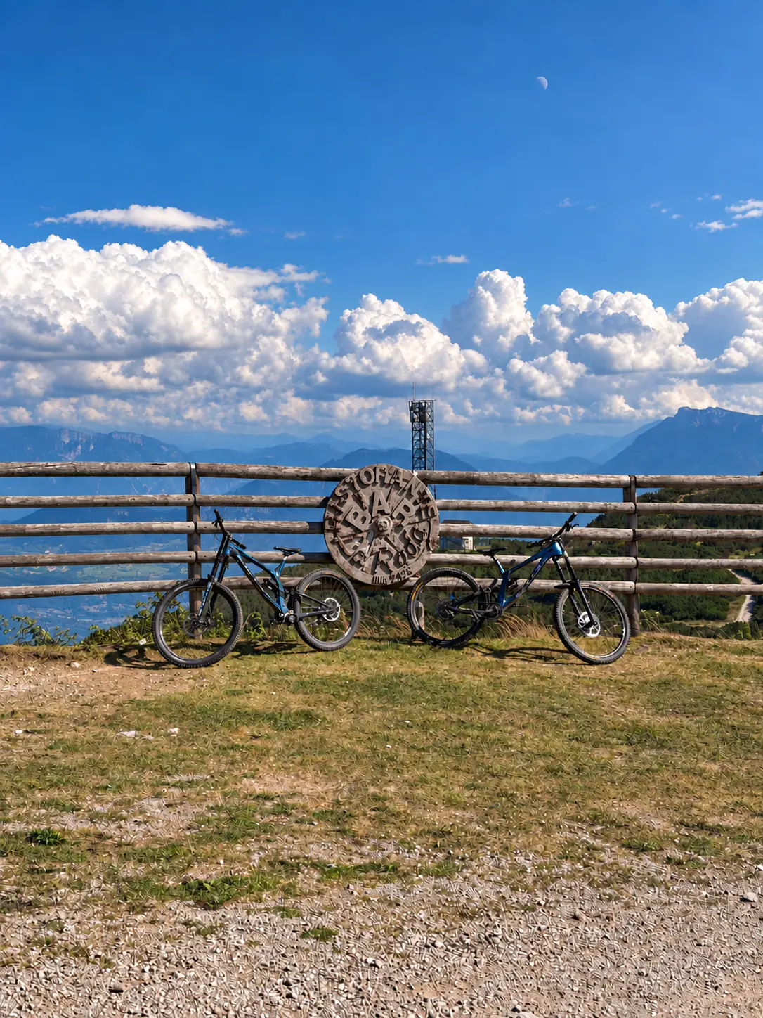 Zwei Downhill-Mountainbikes am Holzzaun vor einem alpinen Bergpanorama
